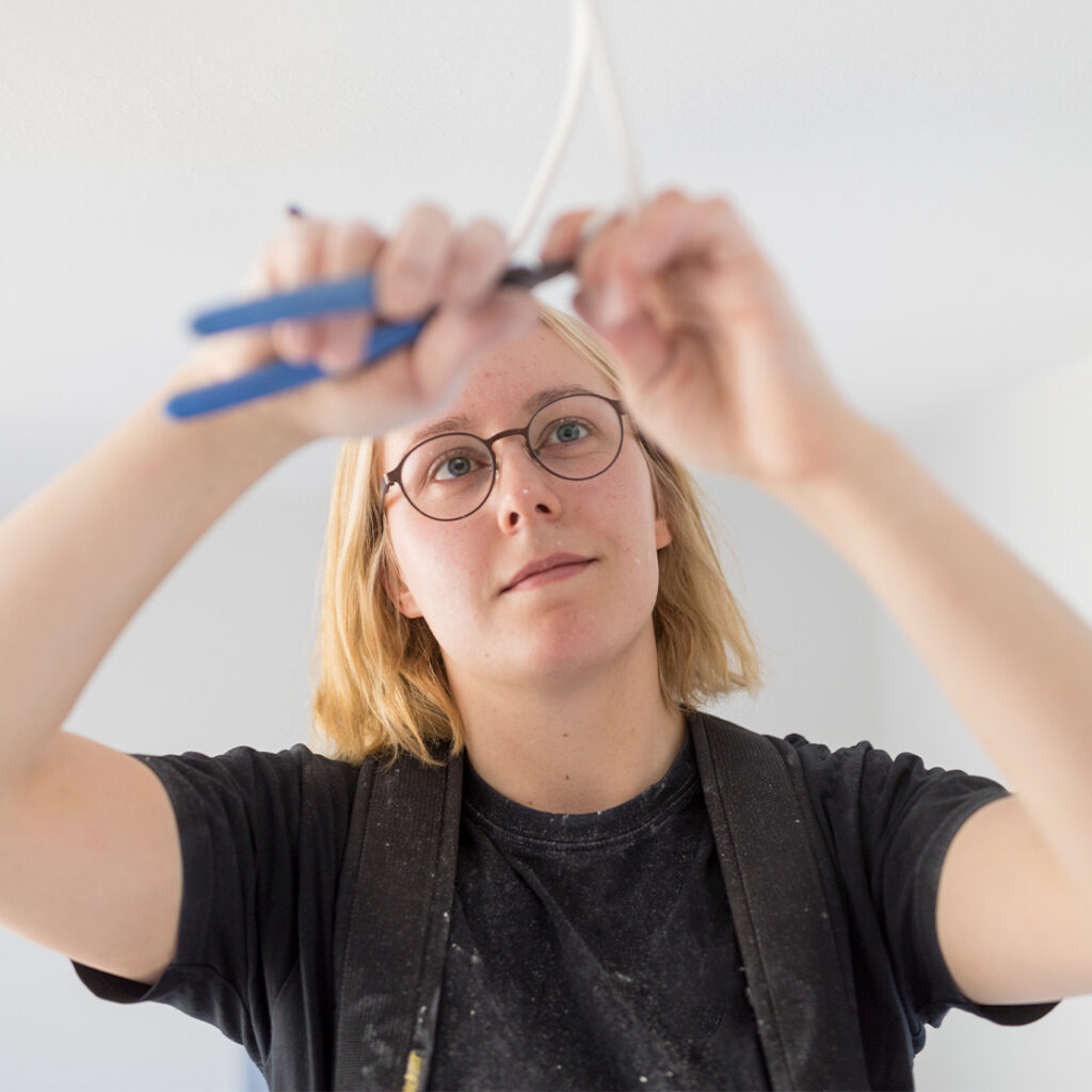 junge Handwerkerin arbeitet mit einer Zange