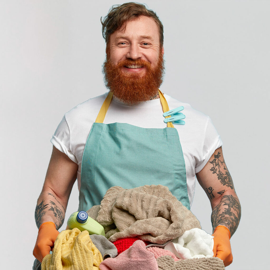 fröhlicher Mann mit rotem Vollbart und Schürze trägt einen Wäschekorb